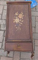 Front view showing floral door, drawer, decorative legs