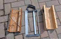 Saw and two mitre boxes laid on paving