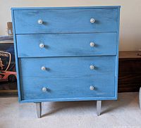 Front view of blue painted three-drawer dresser with six silver knobs