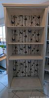 front view of bookshelf showing five shelves and butterfly wallpaper