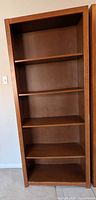 Front view of tall brown bookshelf with five shelves