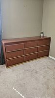Full view of brown nine-drawer dresser against wall