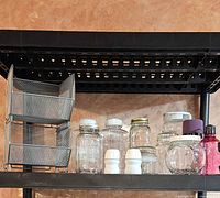 Group shot of mesh organizer and assorted jars, shakers and bottle on shelf