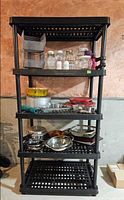 Front view of five-tier black plastic shelving unit standing on floor