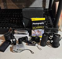 Group shot showing all cameras, binoculars, book and cases