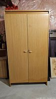 Front view of light wood veneer cupboard with closed double doors