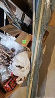 Box containing curtain rings, hardware, wrapped rods leaning on side