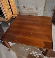 Full view of square wood table showing top and legs