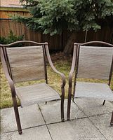 Two brown metal patio chairs on stone patio