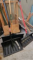 Three different snow shovels standing upright showing scoop and handles