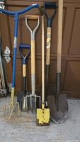 All six garden tools leaning against garage door