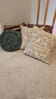 Group view of four throw pillows and round green Aztec calendar wall plaque