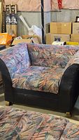 Front view of retro upholstered club chair with abstract fabric and brass feet