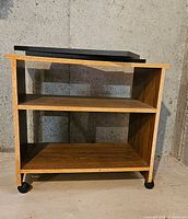 Front view of TV stand showing shelves, casters, and swivel top