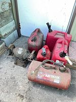 Group shot of bench grinder, air tank and four gas cans