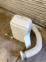 Front view of Insignia portable air conditioner with attached power cord and exhaust hose