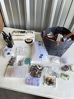 Overall lot view on table showing beads, findings, storage boxes, tote, hand display
