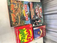 Four board game boxes grouped together: Monopoly Junior Dinosaur Edition, Are You Smarter Than A 5th Grader?, Apples to Apples, Pictionary
