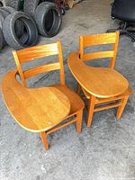 Pair of oak desk chairs showing seats and attached tablets