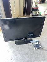 Front view of Philips flat-screen TV on stand with accessories nearby