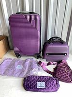Front view of purple spinner suitcase, vanity case, quilted sling bag, quilted purse, foldable tote