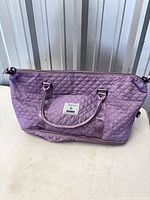 Front view of purple quilted nylon duffel with handles and strap rings