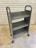 Front angled view of gray three-shelf metal cart on casters