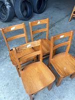 Four oak-finish children's ladder-back chairs front view