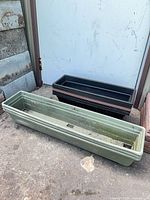 Two stacks of rectangular plastic planters, black and green visible