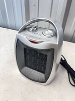 Front view showing silver body, mesh grille, handle, cord