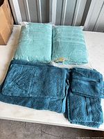 Two packaged bath towels and folded additional towels on table