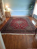 Full view of red Persian style rug in room showing overall design and size