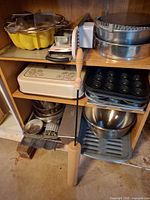 Shelf with Bundt pan, tart molds, springform pans, lidded cake pan, muffin pans, mixing bowls, rolling pin