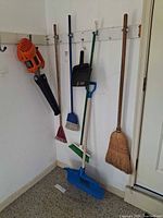 Group of blower, rake, shovel, brooms and dustpan hanging on wall