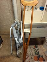 Folding commode and wooden crutches leaning against wall
