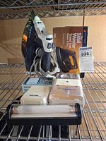 All items arranged on wire shelf: steam iron, travel iron box, Radio Shack listener with box, two lights