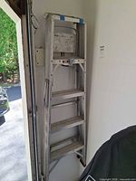 Full view of folded aluminum ladder leaning against wall
