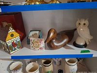 Shelf view with Lenox clocks, wooden duck, owl figurine and decorative house