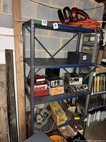 Full view of grey metal 4-shelf unit with assorted items on shelves (contents excluded)