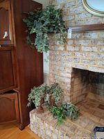Overview of four planters with faux greens on fireplace hearth and shelf