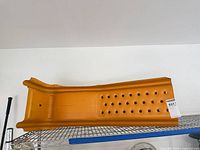 Top view of an orange perforated steel ramp on wire shelf