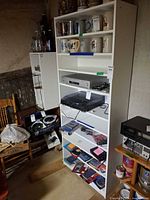 Front view of tall white pressed wood bookshelf filled with various items (not included)