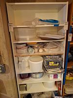 Front view of white pressed board shelving unit loaded with excluded contents
