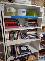 Full view of white pressed board bookshelf with books and bowls (contents not included)