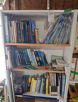 Front view of entire white pressed-board bookshelf with contents present for scale
