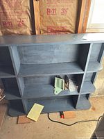 Front view of blue painted wood shelf showing overall design and compartments