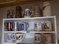 Shelved collection showing 12 steins and mugs across three shelves