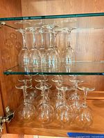 Cabinet shelf with 18 clear stemware pieces, two distinct styles visible