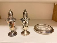 Two metal shakers and glass coaster on shelf