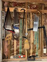 Overall view showing all hand tools hung on wall framing: saws, level, squares, crow bar, plane, broom